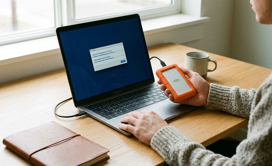 College student backing up laptop files to cloud storage and an external drive